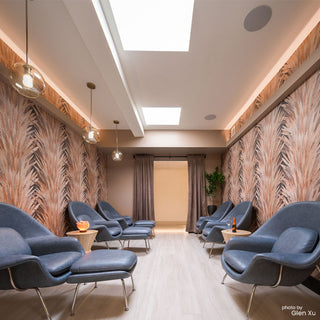 Modern waiting room with blue chairs, patterned walls, and a skylight.