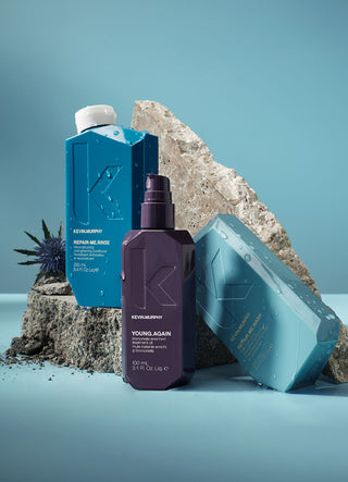 Kevin Murphy product set of 3 products. Shampoo in light blue bottle, conditioner in dark blue, and a treatment oil in a purple bottle. The products are on top of rocks with a sea urchin and the background is light blue. 