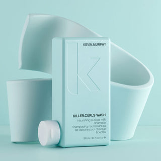 Kevin Murphy Killer Curls Wash shampoo in a 250ml bottle in front of a wavy light blue background.