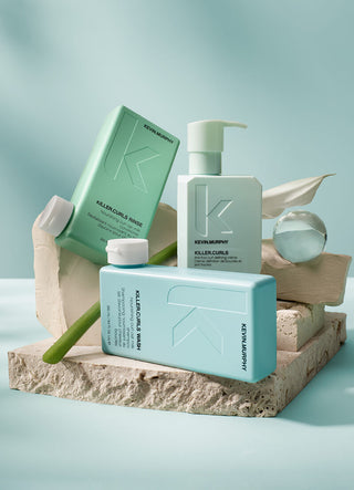 Kevin Murphy hair care products on a stone platform with a light blue background