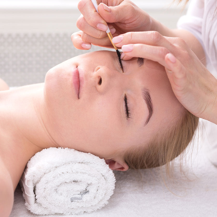 Woman receiving eyelash lift treatment in a spa setting.