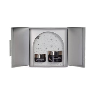 Two skincare jars in a decorative box with a starry night design on a white background