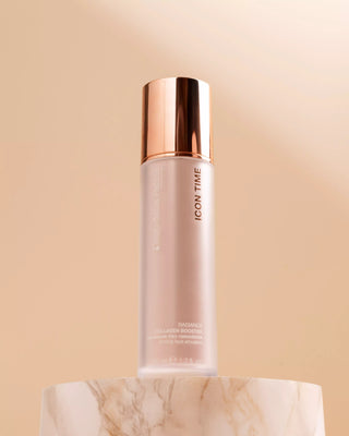 Skincare bottle sitting on marble with bronze cap on a beige background